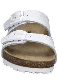 White, textured birkenstock-style sandal with two adjustable straps and silver buckles, featuring a beige cork footbed and white outsole.