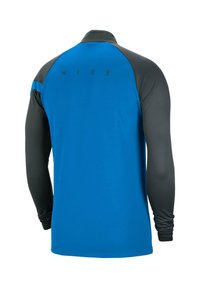 Koszulka sportowa z długim rękawem, niebieski przód i czarne rękawy. Posiada wysoki kołnierz i czarne logo Nike z tyłu. Gładka struktura.