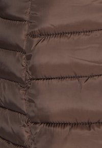 Bruine pufferjack stof met gesteven secties, gladde textuur en zichtbare stiksels, met een slanke, gestroomlijnde uitstraling.