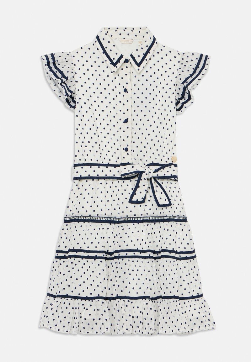 Robe blanche à pois navy. Manches courtes à volants, devant à boutons et taille nouée. Présente des volants superposés au bas et un passepoil contrastant.