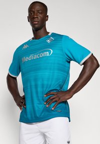 Helles blaues Sporttrikot mit strukturiertem Design, kurzen Ärmeln, rundem Ausschnitt und weißen Akzenten. Das Logo "Mediacom" ist deutlich sichtbar.