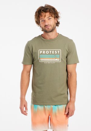Camiseta de manga corta verde oliva con un gráfico rectangular que muestra la palabra "PROTESTA" y rayas horizontales en tonos azules y melocotón.