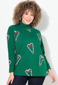 Maglia verde a maniche lunghe con collo alto, decorata con motivi a cuore di bastoncino di zucchero rossi e bianchi, realizzata in un tessuto morbido con una vestibilità rilassata.