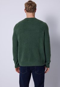 Jersey verde de punto con cuello redondo, puños y bajo acanalados, hecho de material suave, con un corte relajado y textura mínima.