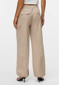 Beige cargobroek met een elastische tailleband, zijzakken en twee achterzakken. Gemaakt van een gladde stof met een losse, ontspannen pasvorm.