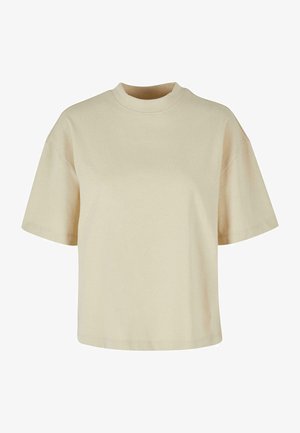 Beżowa bawełniana koszulka z wysokim kołnierzem, krótkimi rękawami i luźnym krojem. Gładka tekstura o prostym, minimalistycznym wzorze.