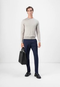 Világosszürke kötött pulóver, tengerészkék nadrág, fekete bőrcipő és fekete táska; sima textúra, testhez álló fazon és egyszerű díszítések.