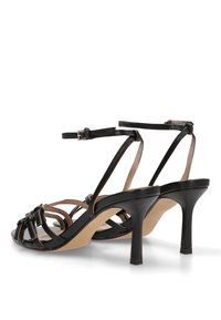 Sandalias de tacón negro con diseño de punta abierta, correas delgadas y cierre de hebilla. El tacón es esbelto y mide aproximadamente 3 pulgadas de altura.