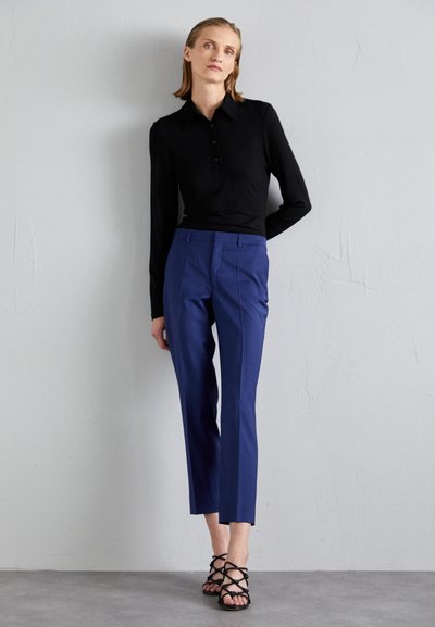 Top lung cu maneci lungi, cu dungi negre și guler, asociat cu pantaloni navy blue croiți și sandale negre cu barete. Texturi fine și un design ajustat.