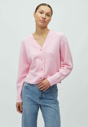 Ružičasti rebrasti kardigan s V-izrezom i pet dugmadi. Dugih rukava, mekane teksture, u kombinaciji s plavim trapericama, na neutralnoj pozadini.