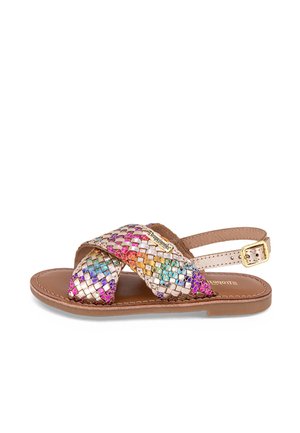 Sandale tressée avec des brides métalliques multicolores, semelle couleur tan et boucle réglable. Design plat adapté à un usage décontracté.