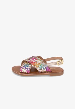 Sandalia tejida con tiras metálicas multicolores, suela marrón claro y hebilla ajustable. Diseño plano, ideal para uso casual.