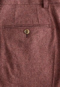 Wollhosen aus einem strukturierten burgunderfarbenen Stoff, mit einerGesäßtasche und einem einzelnen beigen Knopf sowie gesteppten Details.