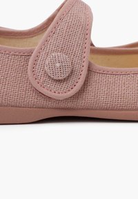 Zapato textil rosa con parte superior de lona texturizada, acento de botón redondo y forro interior beige. Suela de goma plana con un perfil mínimo.