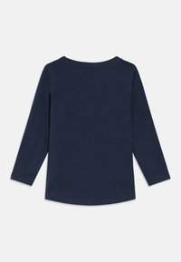 Tumesinine pikkade varrukatega T-särk ümara kaelusega ja sirge lõikega. Valmistatud siledast, kergest kangast; puuduvad nähtavad mustrid või aksendid.