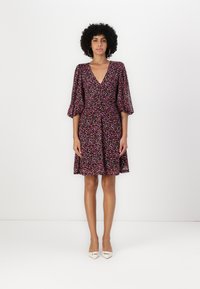 Robe à imprimé floral avec un décolleté en V profond, des manches bouffantes et une taille cintrée. Fabriquée en tissu léger dans des couleurs rose, violet et noir.