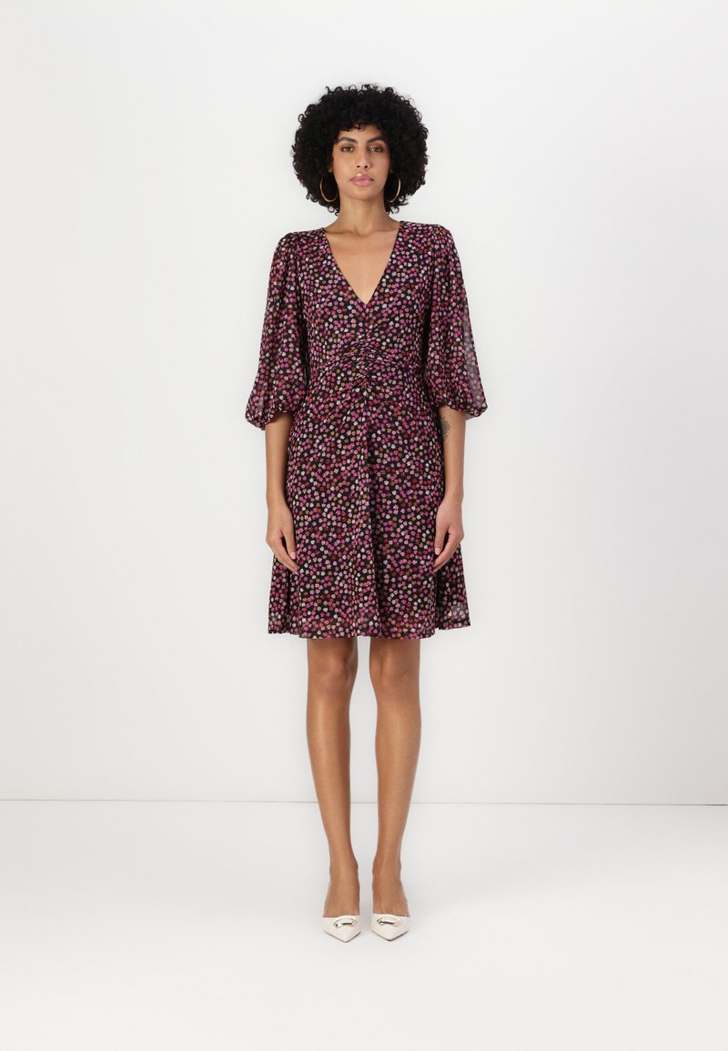 Robe à imprimé floral avec un décolleté en V profond, des manches bouffantes et une taille cintrée. Fabriquée en tissu léger dans des couleurs rose, violet et noir.
