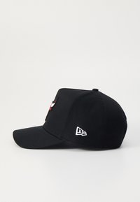 Schwarze Baseballmütze mit einem gestickten Logo auf der Vorderseite und einem kleinen Logodetail an der Seite, gefertigt aus einem Stoff mit glatter Oberfläche.
