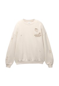 Sweat-shirt beige à manches longues avec des trous usés et le texte "L.A. Coyote California Inn" sur la partie supérieure gauche de la poitrine.