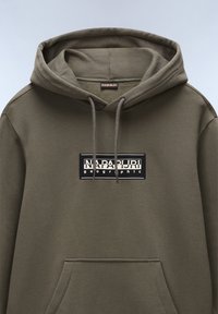 Hoodie vert olive en matière douce, avec une poche kangourou à l'avant et un patch logo avec du texte noir et blanc. Capuche avec cordon de serrage ajustable.