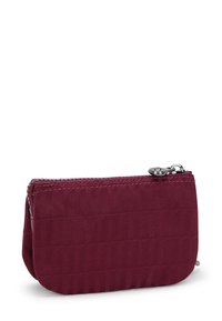 Burgundy tygplånbok med dragkedjestängning, slät yta, kviltat mönster och detaljer i silver på dragkedjans drag.