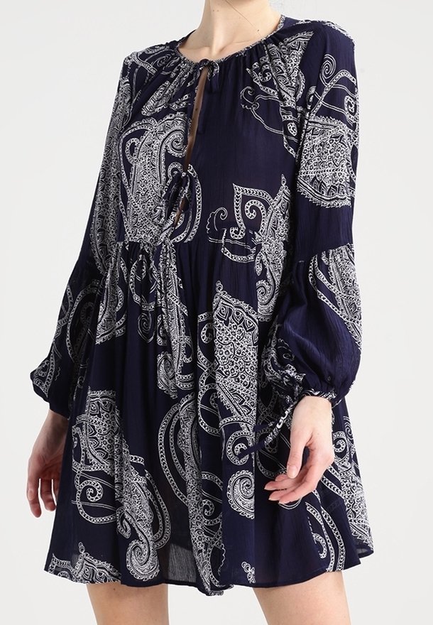 Marineblaues Kleid mit Paisleymuster, langen gepufften Ärmeln und gerafftem Bund. Es hat einen runden Ausschnitt und ein Knopfdetail an der Vorderseite.