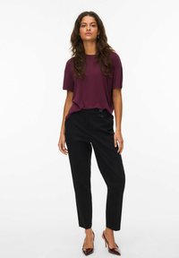 Burgundyröd kortärmad topp i kombination med svarta skräddarsydda byxor och mörk burgundyröda klackar. Outfiten har en avslappnad passform och slät tyg.