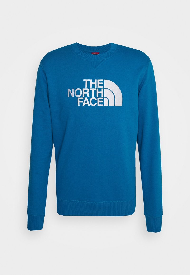 Sweat-shirt bleu à col rond, manches longues et poignets côtelés. Présente un grand logo blanc avec le texte "THE NORTH FACE" à l'avant.
