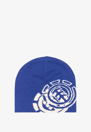 Blauwe gebreide muts met een groot wit cirkelvormig abstract patroon aan één kant, plat uitgestald op een witte achtergrond.