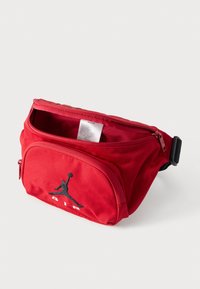 Κόκκινο τσαντάκι μέσης από ύφασμα με κύριο διαμέρισμα με φερμουάρ, μπροστινή τσέπη με φερμουάρ και μαύρο λογότυπο Air Jordan. Περιλαμβάνεται ρυθμιζόμενος ιμάντας.