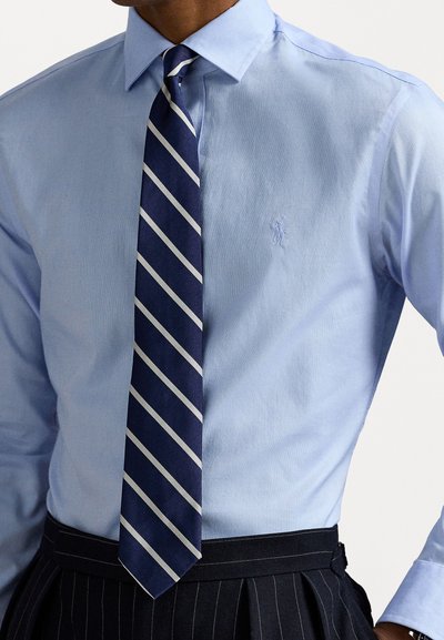 Camisa de vestir azul claro com colarinho pontudo, combinada com uma gravata riscada azul-marinho com detalhes brancos. Tecido texturizado e design slim fit.