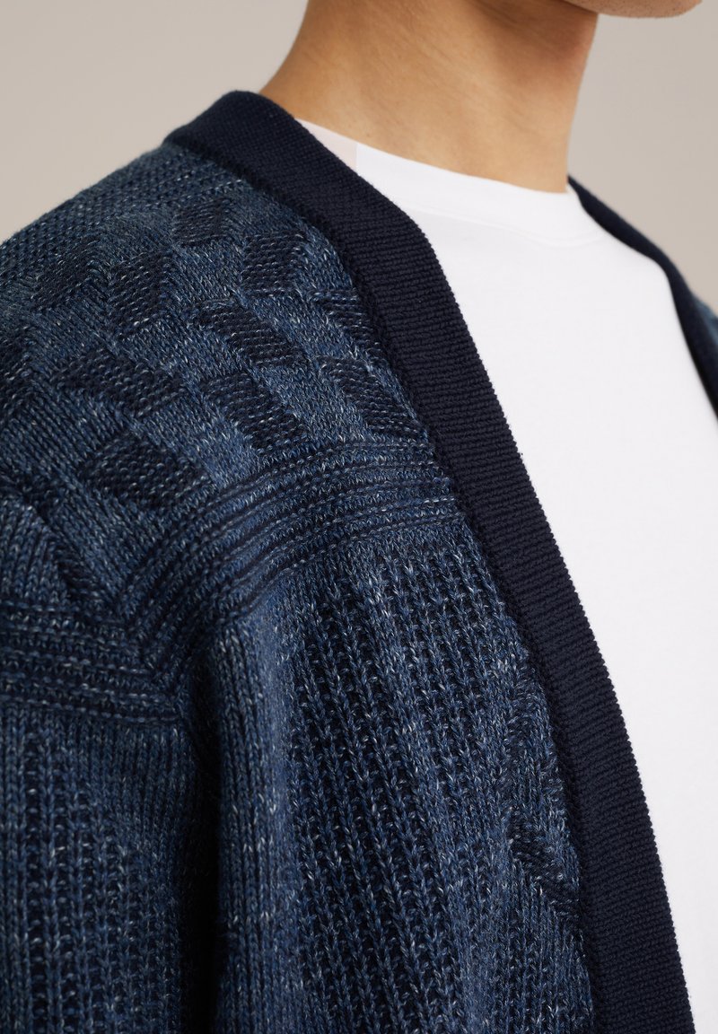 Navy textuur cardigan met een geometrisch breipatroon, contrasterende effen kraag en een zachte, lichte stof.