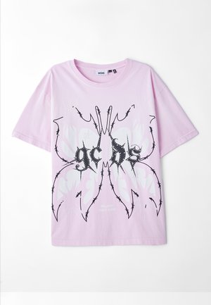 T-shirt in cotone rosa con una grafica in bianco e nero che ricorda una farfalla con accenti simili a spine e del testo sottostante.