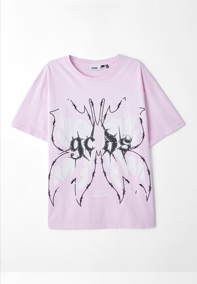 T-shirt en coton rose avec un design graphique noir et blanc ressemblant à un papillon avec des accents en forme d'épines et du texte en dessous.