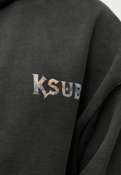 Σκούρα γκρι φούτερ με το κείμενο "KSUB" σε πολύχρωμη, υφή γραμματοσειρά στην αριστερή περιοχή του στήθους. Απαλό υφαντό ύφασμα.
