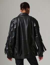 Μαύρο δερμάτινο μπουφάν με υφασμένα κρόσσια στα μανίκια, σε χαλαρή εφαρμογή και με ζωνάρι που σφίγγει στη μέση. Οπισθοσκόπηση.