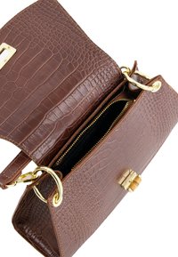 Brun krokodille-embossed læder håndtaske med hardware i guld-tone. Har en lynlåslomme og klipslukning. Tekstureret overflade og struktureret form.