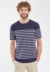 Marineblå kortærmet t-shirt med vandrette hvide striber. Har rund halsudskæring og en lille orange logo-detajle nær kanten.