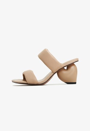 Beige hakken sandalen met twee brede banden, een vierkante neus en een hartvormige malle hiel. Gemaakt van glad leer met een matte afwerking.