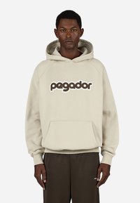 Μπεζ φούτερ με μπροστινή τσέπη και μεγάλο λογότυπο «pagador» σε καφέ και λευκό. Διαθέτει κουκούλα με κορδόνι και ριμπ μανίκια.