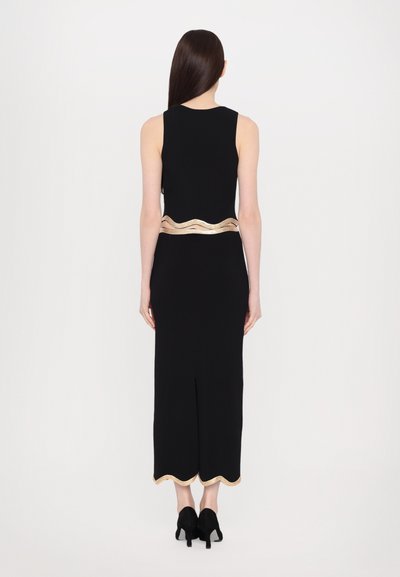 Black sleeveless dress featuring a wavy gold accent at the waist, slit at the back, and scalloped gold trim at the hem.