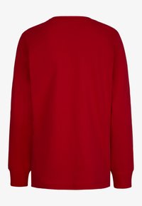 Punainen pitkähihaiseen t-paita, joka on valmistettu puuvillasta. Siinä on pyöreä pääntie, suora helma ja täydet hihat ribbauspäillä. Yksinkertainen, tasainen design.