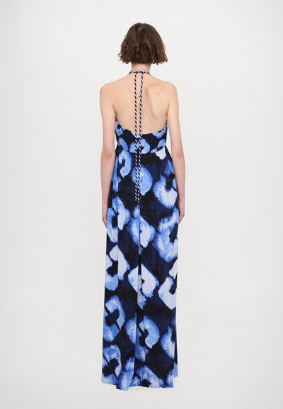 Robe longue sans dos avec un motif floral dans des tons de bleu et de noir. Présente un design à col halter avec un détail de nœud rayé à l'arrière.