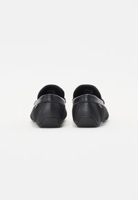 Des chaussures noires à enfiler avec un dessus en cuir lisse et des détails en mesh, dotées d'un bout arrondi et d'un talon minimaliste, conçues pour le confort.