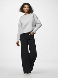 Sivý crewneck sveter s padnutými ramenami, skombinovaný s čiernymi širokými nohavicami a bielymi teniskami. Hladká a textúrovaná tkanina.