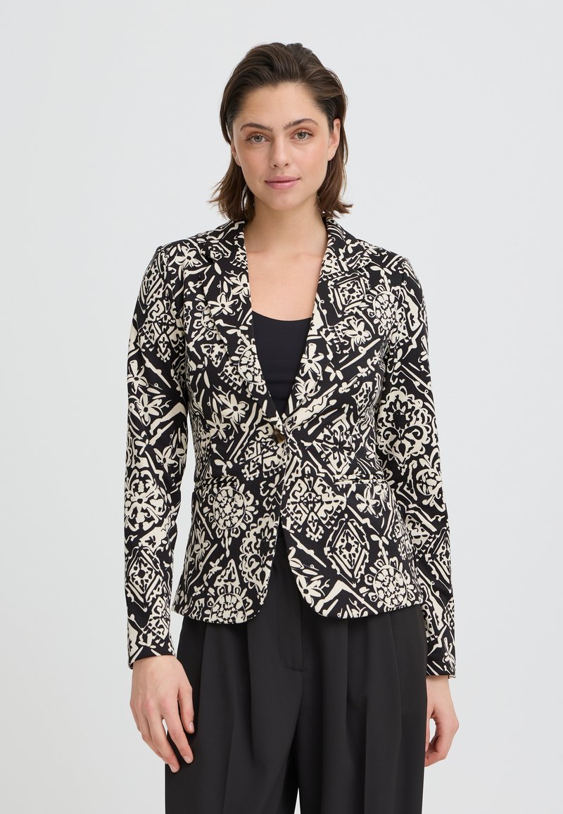 Blazer noir et crème à motif, coupe ajustée, col à revers cranté et manches longues. Présente des motifs floraux et géométriques élaborés.
