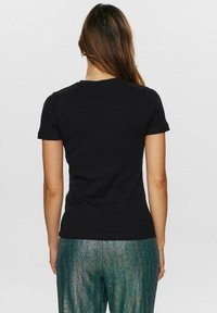 Tricou negru cu maneci scurte, cu un design ajustat, având o guler rotund și un material din bumbac neted și elastic. Purtați-l cu pantaloni strălucitori, cu textură.