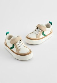Weiße Sneakers mit beigen Wildleder-Details, grünem Muster an der Seite, Schnürung mit Klettverschluss, weißer Gummisohle und grünem Fersentab.