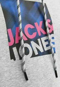 Sudadera gris con un gran estampado gráfico en negro y rosa, con un patrón de semitonos azules. Incluye detalles en gris y negro en los cordones.