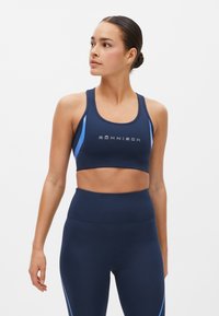 Sujeción deportiva de color azul marino con acentos en azul claro, que presenta un escote redondeado y texto de logo. Tejido suave y elástico, diseño de espalda nadadora.